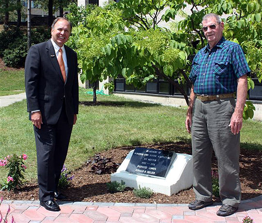 President Anderson and Donald Holzer stand near the garden.