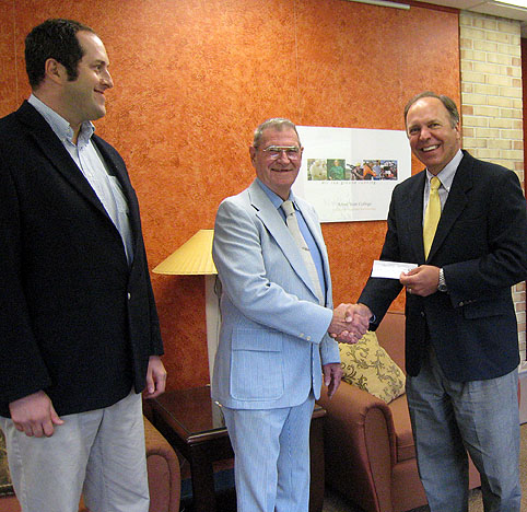 Donald Holzer presents a check for two scholarships.