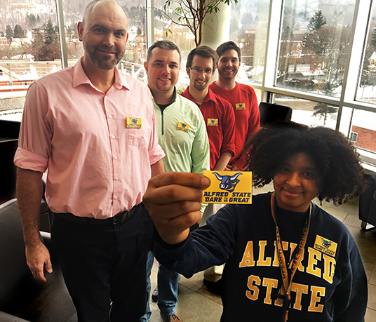 employees holding their “Alfred State: Dare to be Great" pins