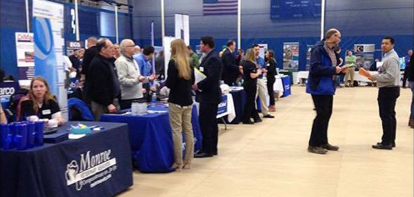 employers and students at tables in the gymnasium