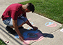 student drawing on sidewalk with chalk