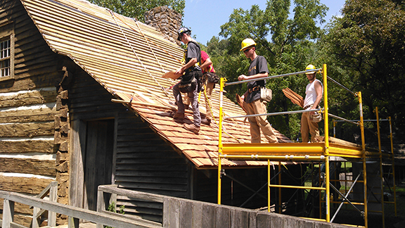 students working on the roof of a house