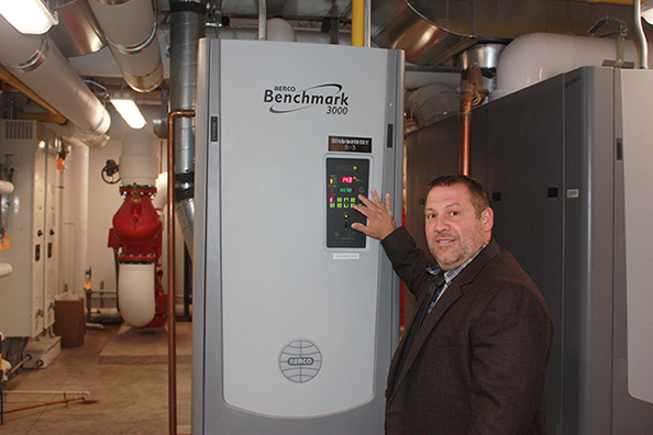 Senior Director of Facilities Services Glenn Brubaker poses with a new energy efficient satellite boiler