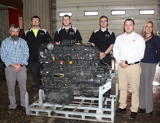 six people standing around a large engine