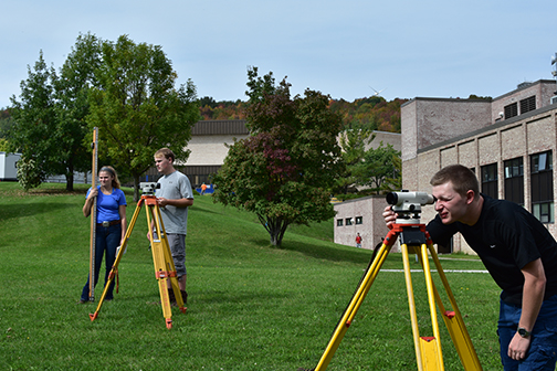 three surveying students using equipment outside
