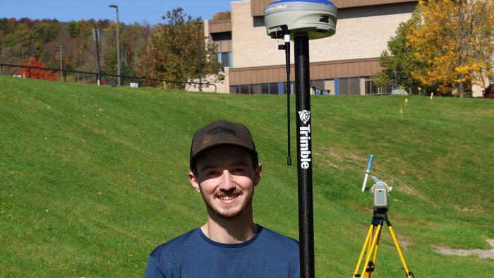 Adam Estes stands with surveying equipment