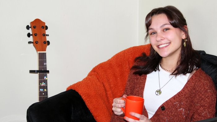 students sits in her dorm room with a warm drink