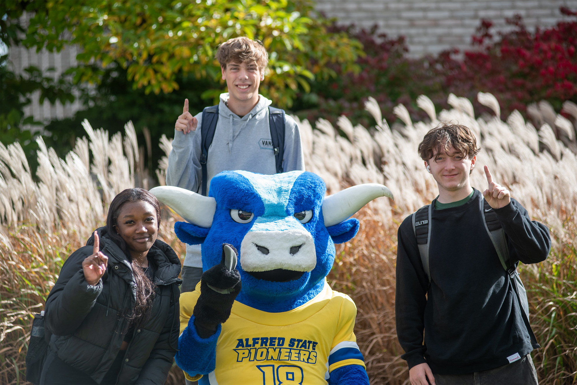 Three Alfred State students with mascot Big Blue giving the #1 sign.