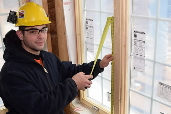 Aaron Aumick holding a ruler next to a window