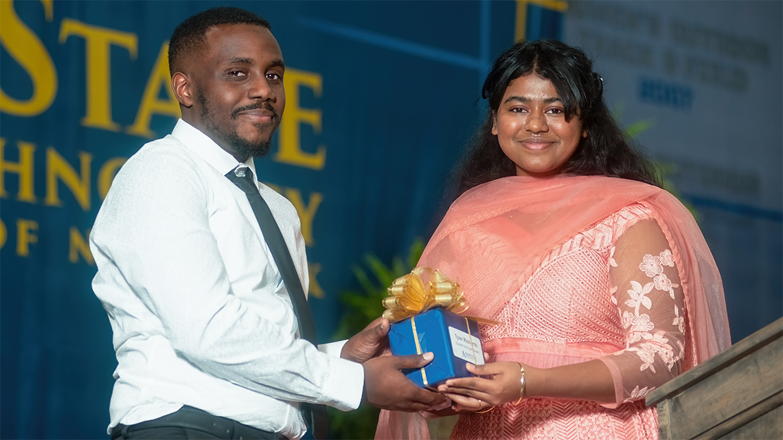 Tyler Richards, the Residence Hall Director in Braddon Hall, receives the Alfred State Student Advocate Award from Student Senate President Soumya Konar.