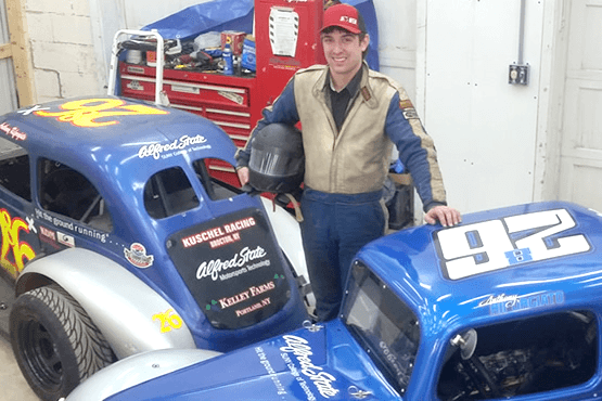 Anthony Riforgiato standing next to two cars