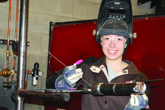 Deborah Huppman holding some welding equipment wearing a helmet