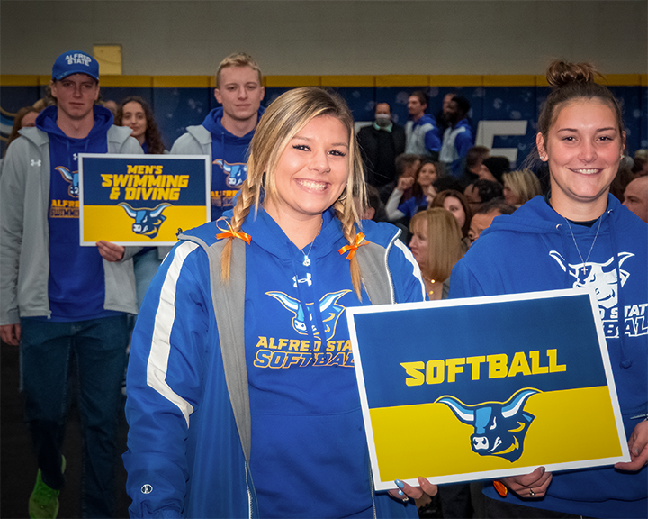 Softball team players represent their team in the Pioneer Parade that featured representatives from athletic teams, clubs & organizations, and acadmics