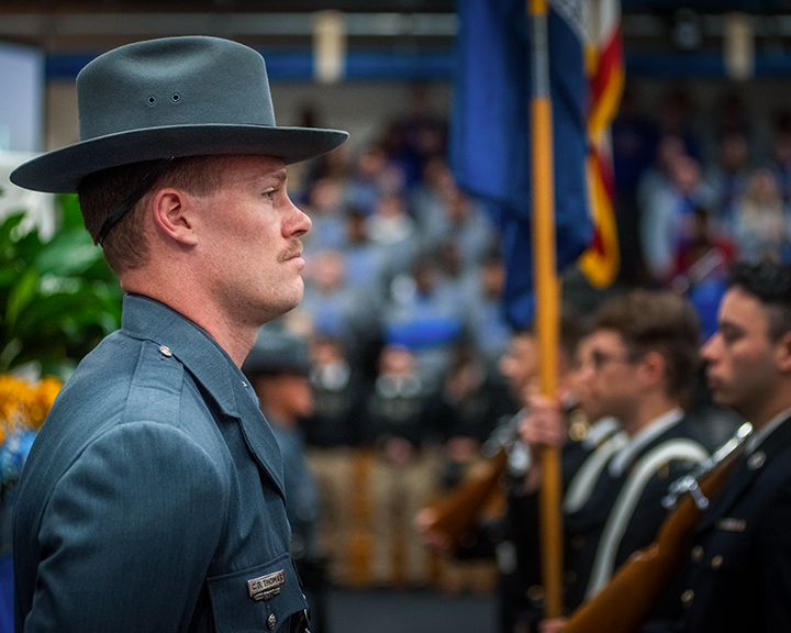 University Police Officer stands in front of stage as ROTC presents the colors