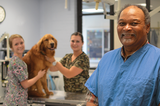 Dr. Mel Chambliss with 2 students and a dog in a lab