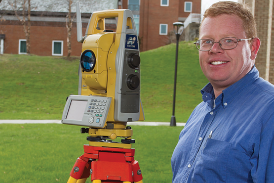 Roger O’Toole next to surveying equipment