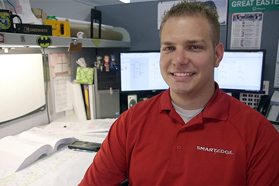 Taylor Battaglia sitting in his cubicle at work