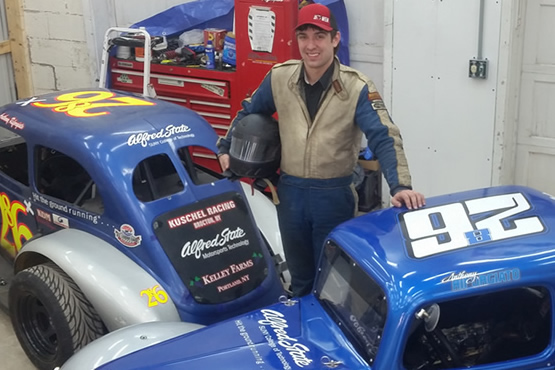 Anthony Riforgiato standing next to two cars