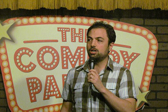 Chad Dispenza at the comedy club, holding a microphone