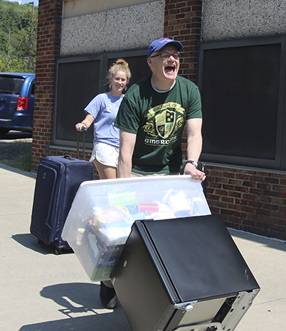 female with suitcase and male rolling a fridge