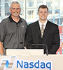 Adam Wilkins with his dad in front of Nasdaq podium, Times Square can be seen thru the window in background