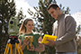 two students outside with survey equipment