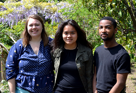 three students standing in front of trees