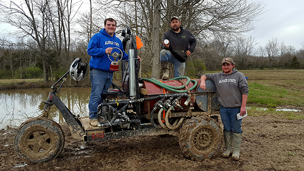 three male students standing next to a basic utility vehicle