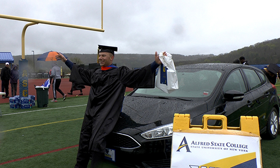 Garrett Mack with hands in the air in front of a black car