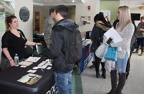 woman standing behind a table speaking with students