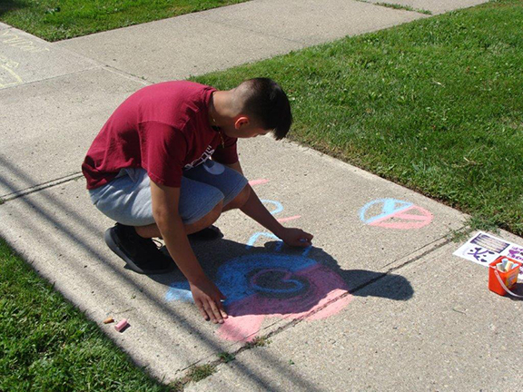 student drawing on sidewalk with chalk