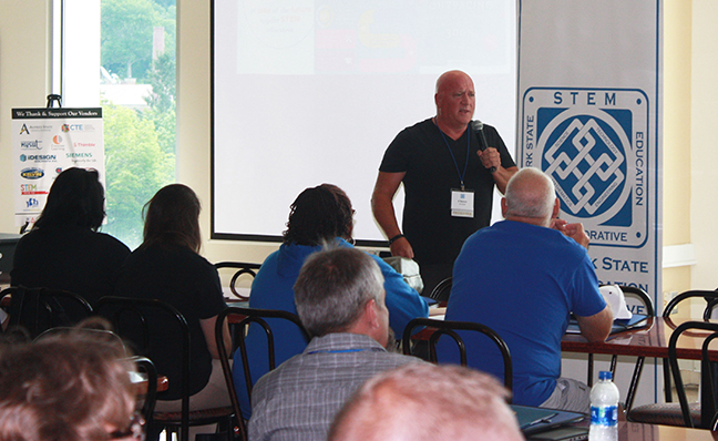 Dr. Clint Ballinger standing in front of audience with microphone