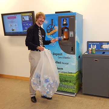 Man poses while putting a bottle into the machine