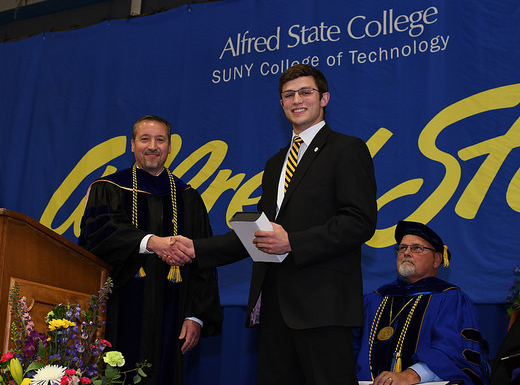 student Grant Tinker shakes hands with Dr. John Williams