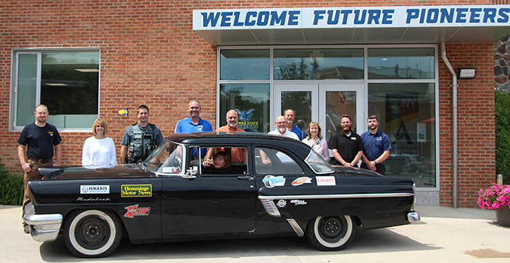 several people standing behind a car