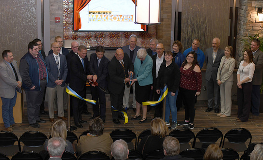 several people standing behind a ribbon being cut