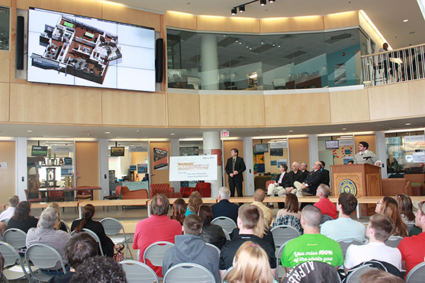 Mach Architecture Executive VP Douglas Schaefer, near the sign, and Associate Robert Brunner, at the podium, speak during the unveiling of “MacKenzie Makeover”