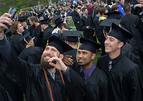 three male students at Commencement taking a selfie