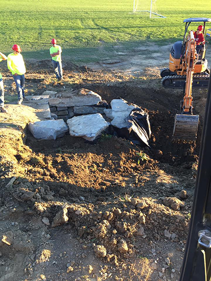 student operating a piece of heavy equipment to move large stones