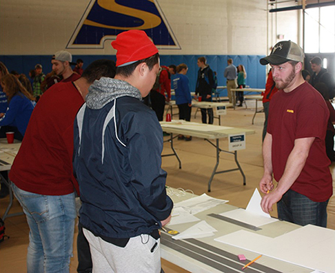 Zachary Herrington assists students with a National Engineers Week design challenge.