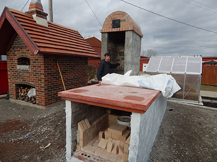 student standing outside next to brick ovens