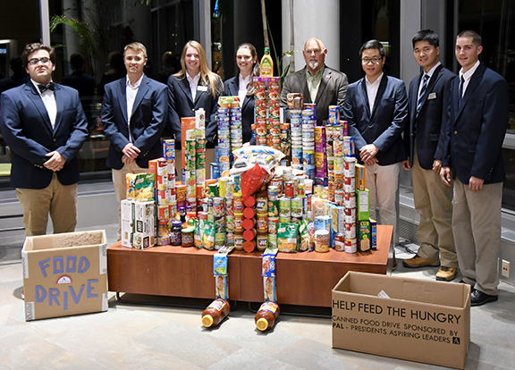 students wearing blue suite coats in front of cans of food