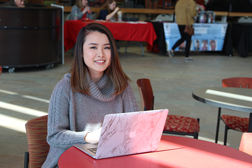 Riko Hayano sitting at a table with her laptop