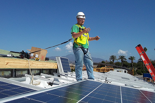 Ryan Kozlowski, an Alfred State electrical construction and maintenance electrician major from Buffalo, is surrounded by solar panels on the top of Team Alfred’s entry in the 2015 US Department of Energy Solar Decathlon