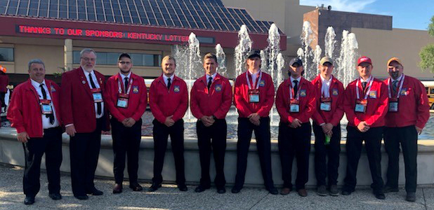 several men wearing red coats standing in front of a water fountain