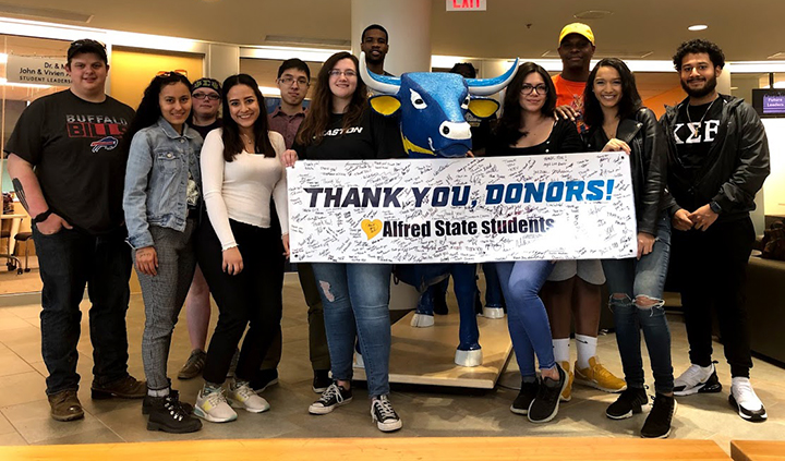 several students holding a banner that says thank you, donors