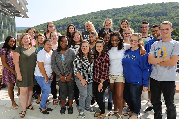 several students posing for the photo, standing outside, hill in the background