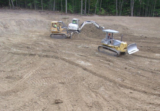 students driving bulldozers (2) and lots of dirt