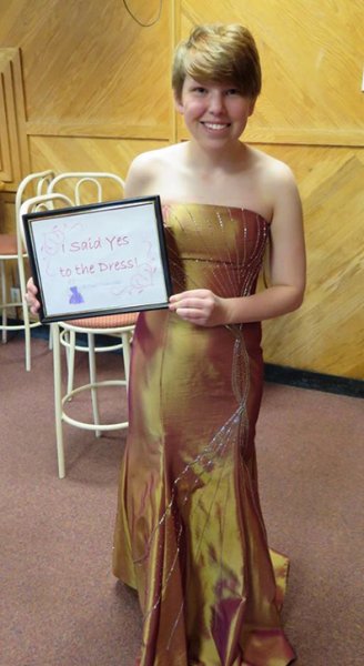 Kaitlyn Cook wearing a prom dress and holding a sign that says 'i said yes to the dress'