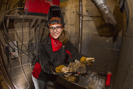 Emily Slayton wearing a welding hat and protective gear